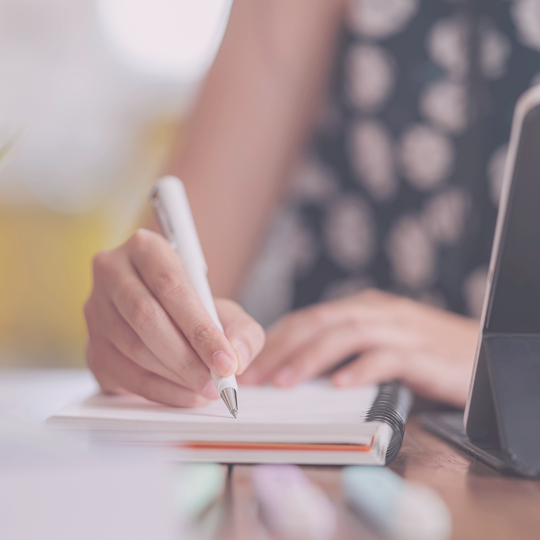 Close-up of a hand holding a pen and writing in a notebook