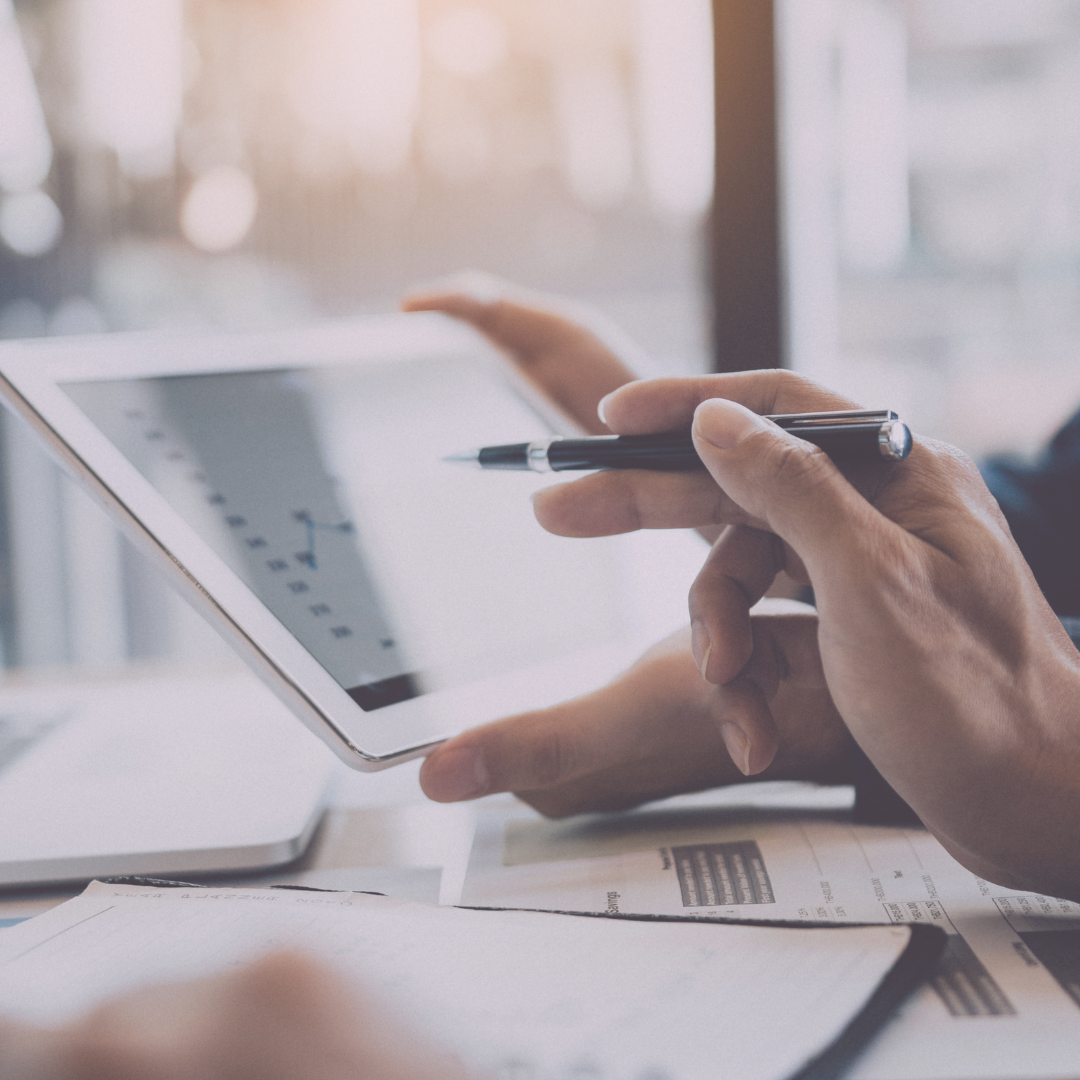 Close-up of a hand holding a pen pointing at a tablet