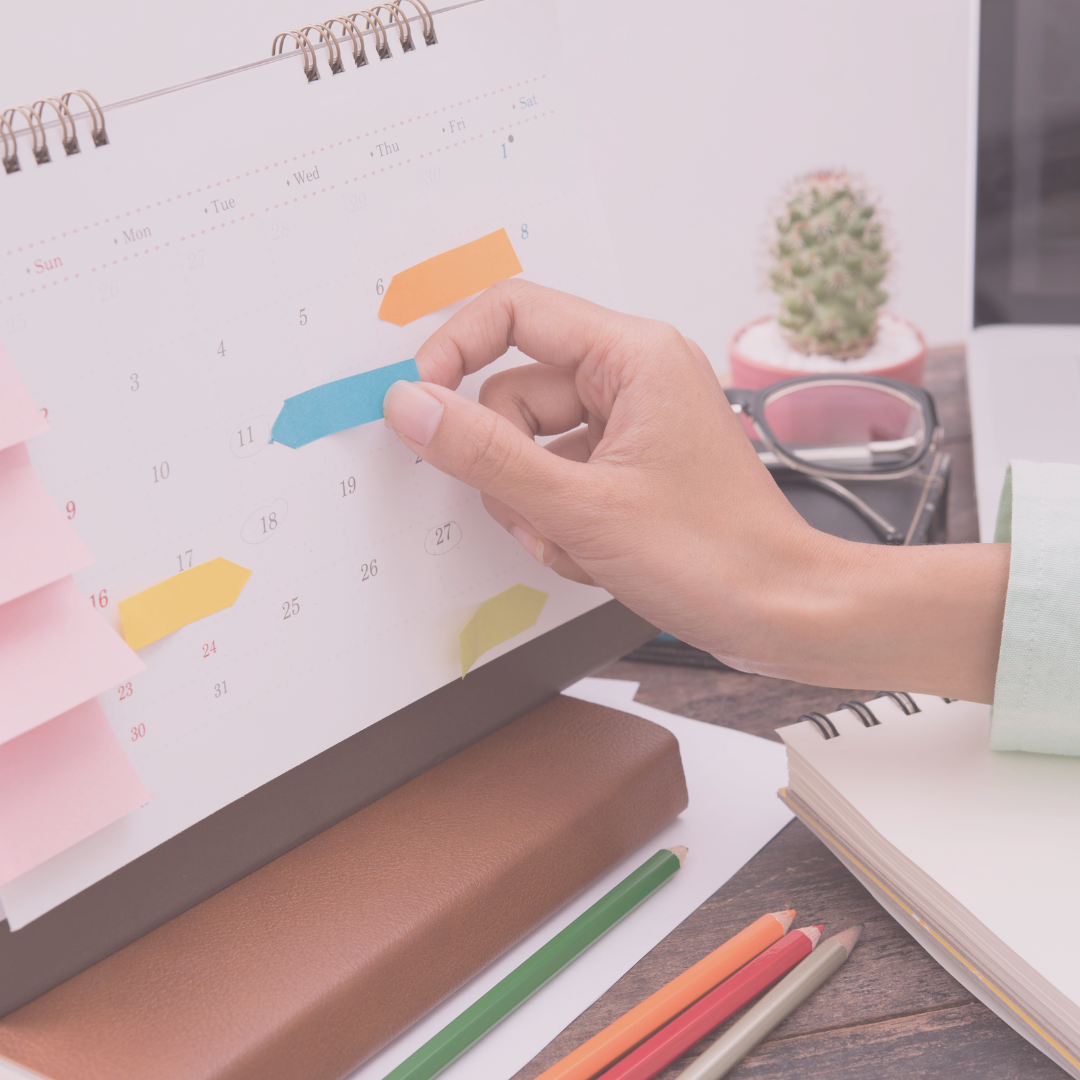 Close-up of a hand placing a sticky note on a calendar