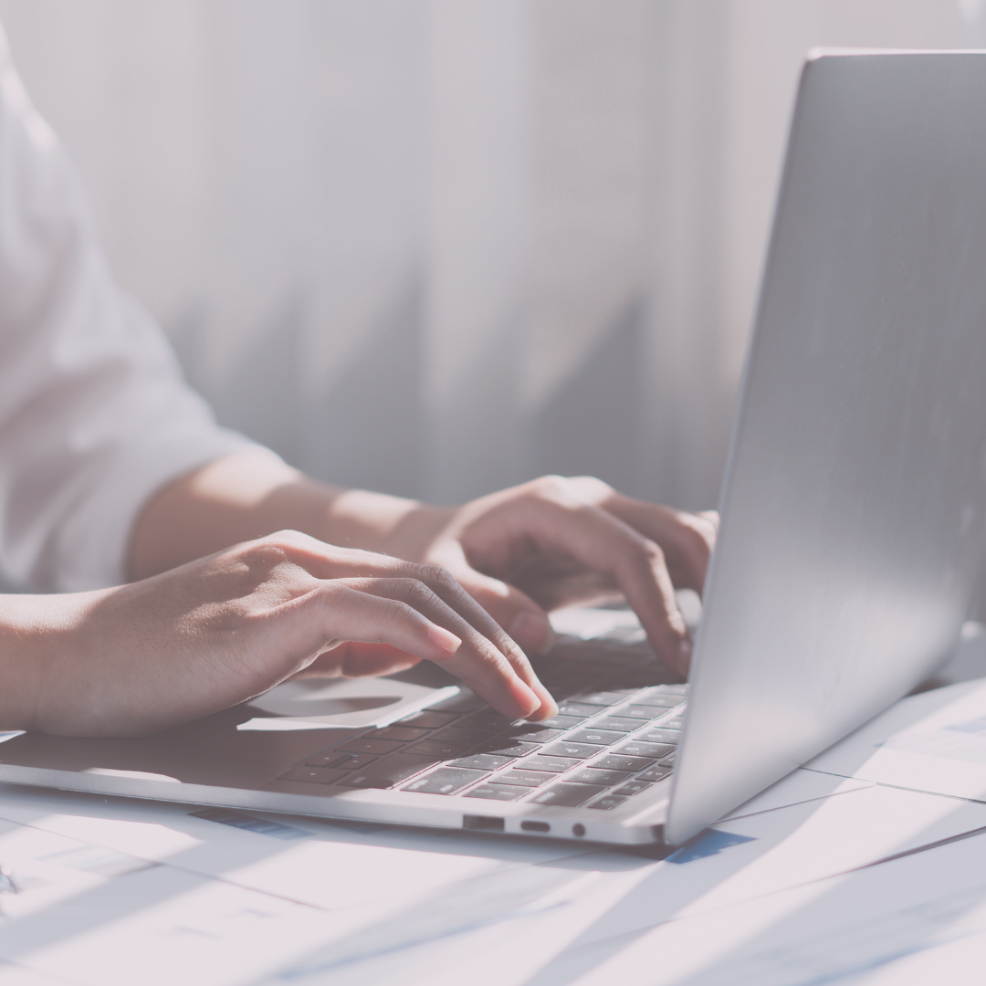 Close-up of hands typing on a laptop keyboard